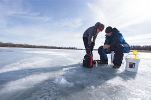 Two ice anglers ice fishing on a frozen lake