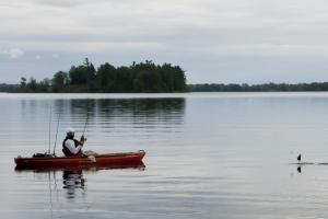 Angler on a lake reeling in a fish from his kayak