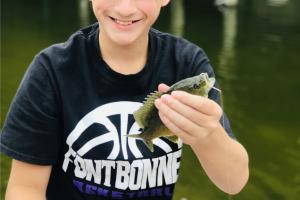 Boy angler hold up a small perch at Bass Pros gone fishing event